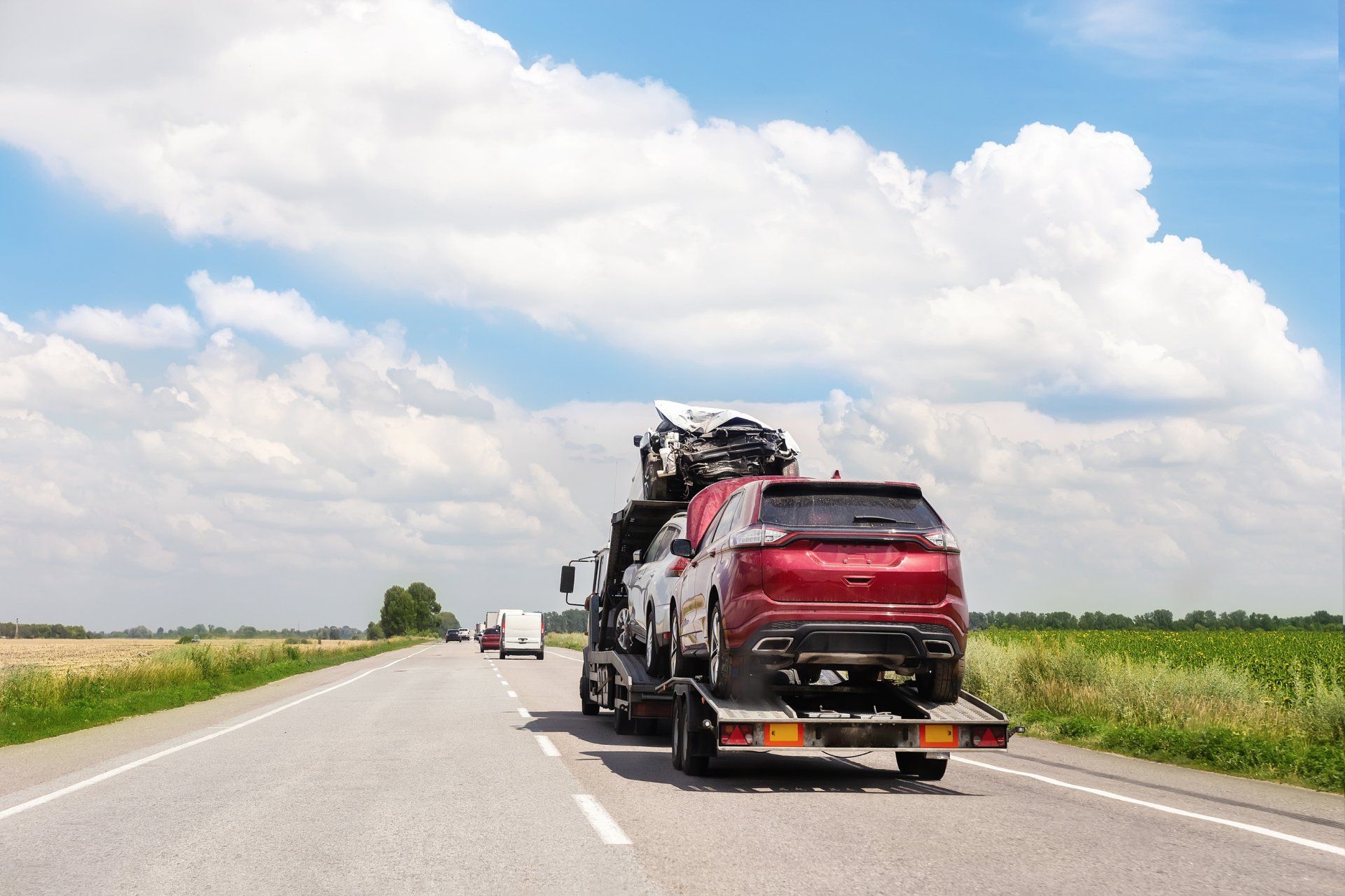 Recovery truck transporting a car along a main road