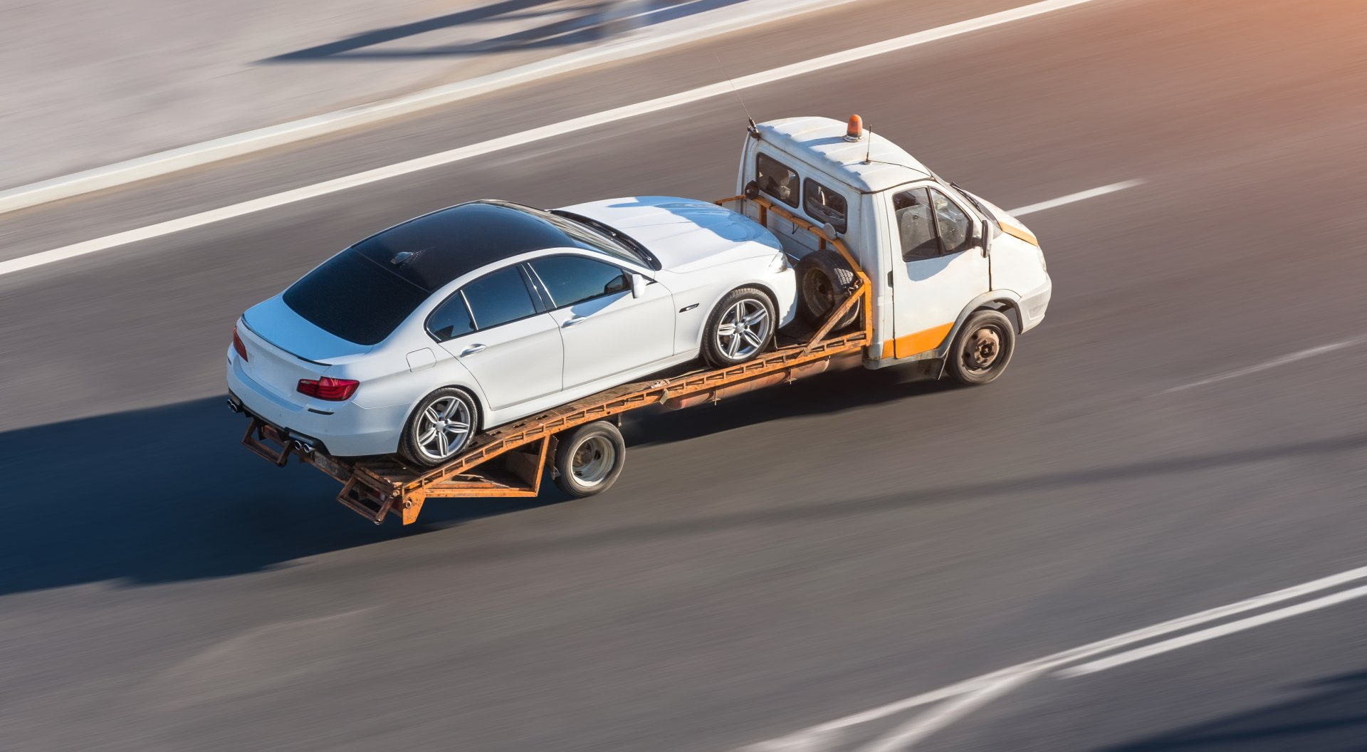 Recovery truck carrying a car at speed on the road